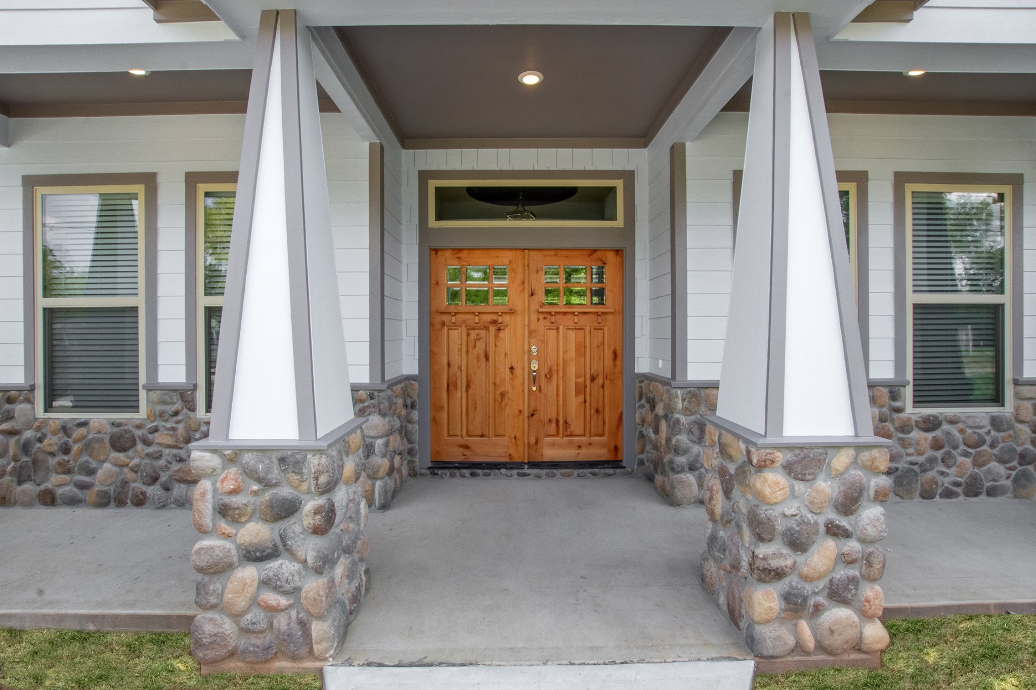 Everline Homes covered front entry with knotty alder double doors and river rock columns