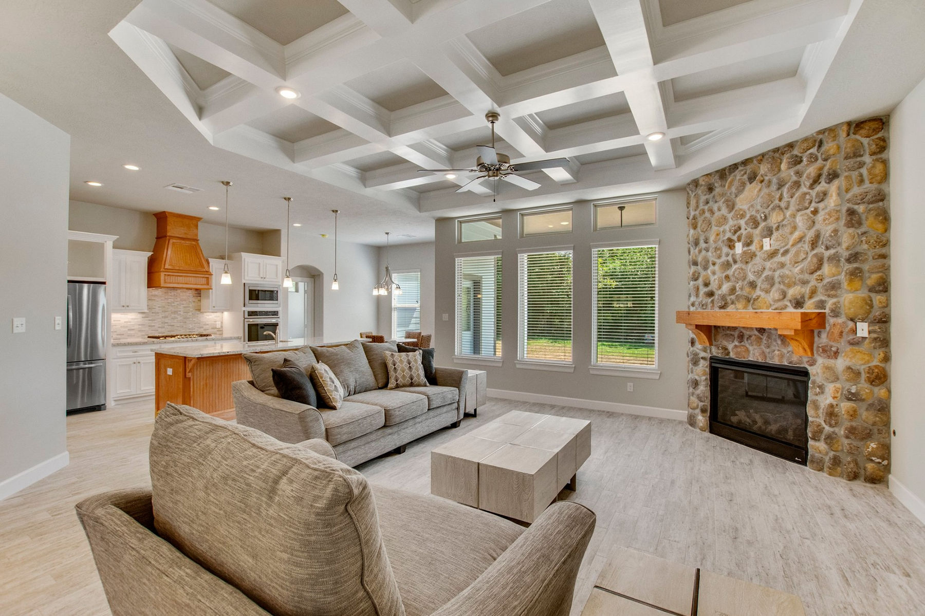 Everline Homes great room with coffered ceiling, copper vent hood and stone fireplace