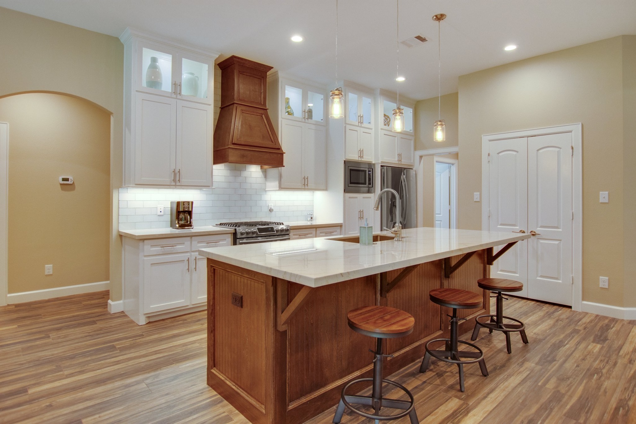 Everline Homes kitchen with a custom wood vent hood, quartz island and bar seating
